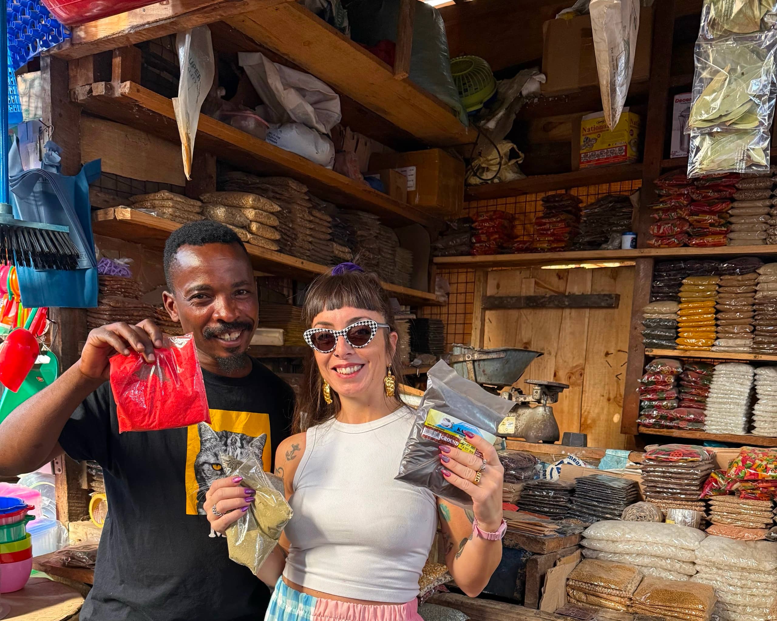 A traveller and a local guide laughing in a spice and textile shop in an Arusha market