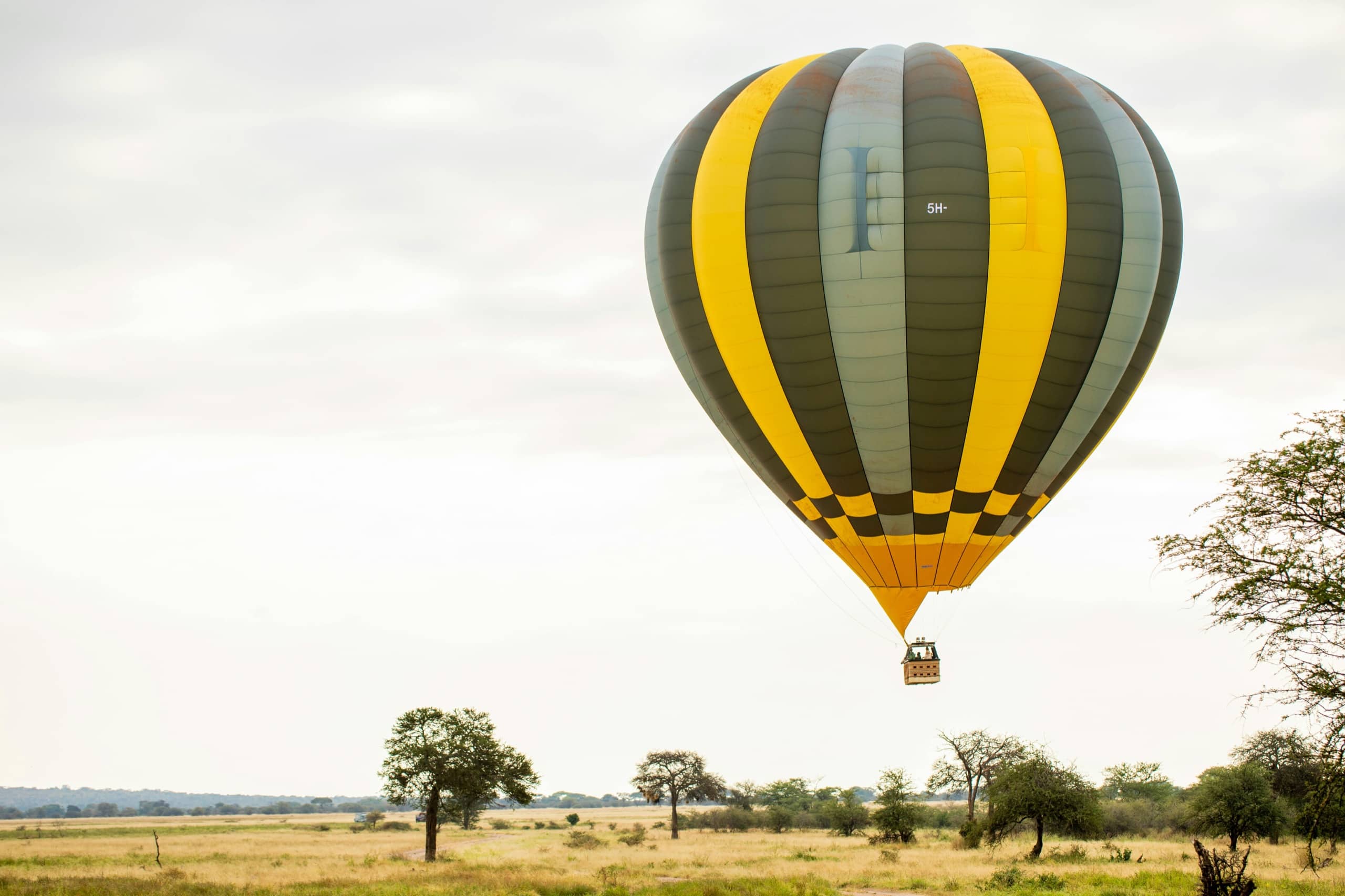 A hot air balloon drifts low over the Serengeti plains at sunrise
