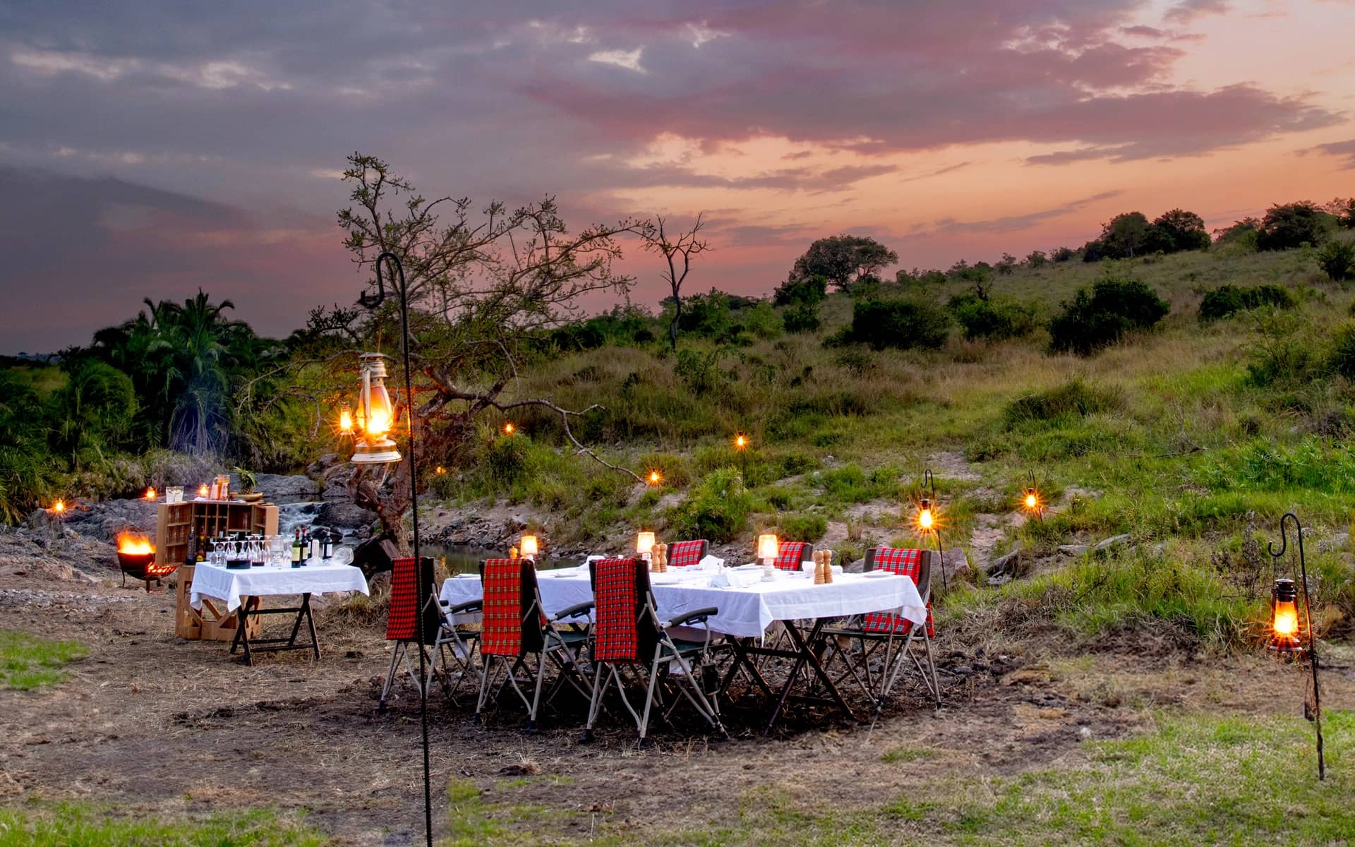 A lantern-lit private dinner set in the bush after a day on safari