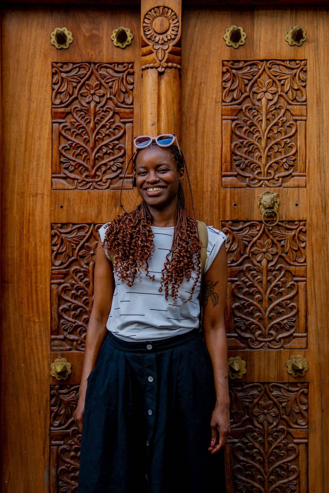 A traveller smiling in front of a carved wooden door in Stone Town, Zanzibar